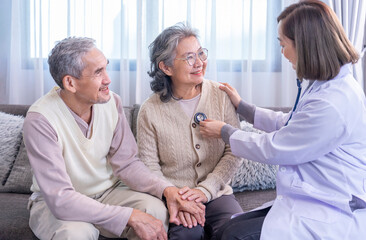 Obraz premium senior couple being examination from a doctor in uniform,using stethoscope listening on chest old woman,her husband holding hands to give encouragement