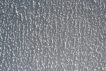 Close-up, background texture of a beige-white facade wall of a house made of decorative plaster. Abstract surface.
