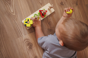 Little boy playing with educational wooden toy at home. top view. Concept of early child development, learning through play and fine motor skills. space for text