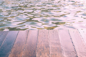 Wooden deck, tabletop on the surface of the water against the background of the pool.