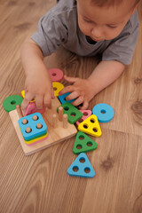little baby playing with geometric figures. learning colors. Concept of early learning through play, fine motor skills and early childhood development.