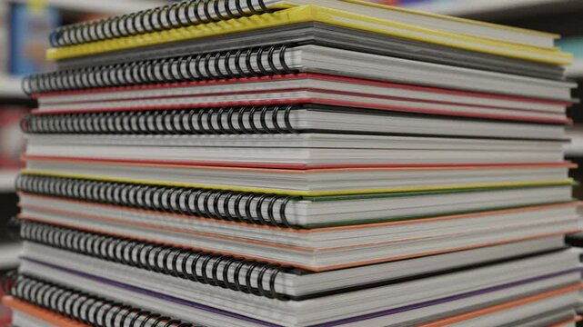 Stack of Spiral Notebooks: A high stack of colorful spiral notebooks showcases various colors and textures, perfect for back to school or office organization. 