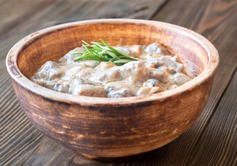 Hearty beef stroganoff in rustic bowl, garnished with fresh aromatic rosemary