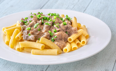 Beef stroganoff with rigatoni pasta, topped with fresh green onion garnish