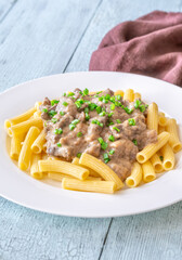 Beef stroganoff with rigatoni pasta, topped with fresh green onion garnish