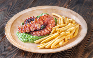 Baked Octopus With Creamy Spinach And Fries On A Rustic Plate