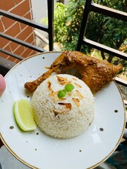 Chicken stew and rice dish served on a white plate on a wooden table. Delicia African chicken stew with rice. Soy Fried Chicken with Rice. 