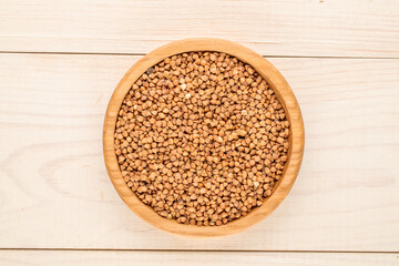 Raw buckwheat with kitchen utensils on a wooden table, top view, macro.