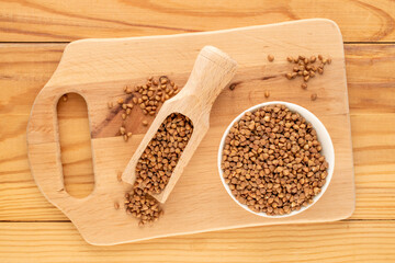 Raw buckwheat with kitchen utensils on a wooden table, top view, macro.