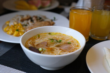 asian style rice soup with herbs in a bowl , fresh salad and milk , orange juice. High quality photo