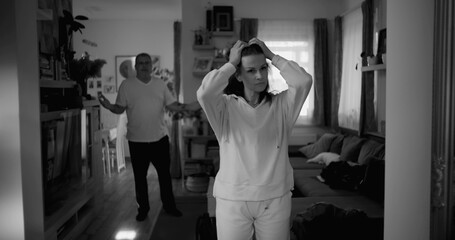 Woman holding her head in frustration during heated argument, while man in background gestures...
