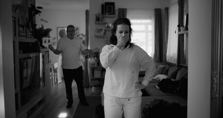 Fototapeta premium Woman holding her head in frustration during heated argument, while man in background gestures angrily, capturing intense conflict and emotional distress in a couple’s relationship