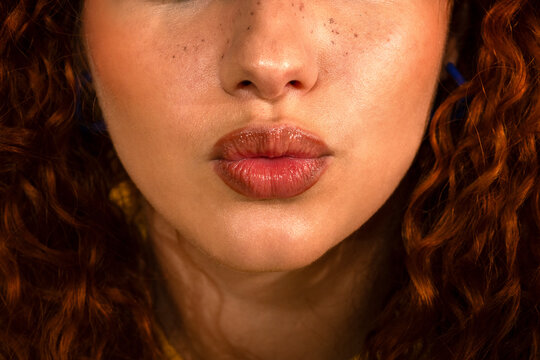 Close-up of lips with vibrant red curly hair