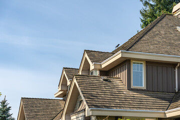 Top of grey stucco luxury house with shingle roof, green trees and nice windows in Spring in Vancouver, Canada, North America. Day time on April 2025.