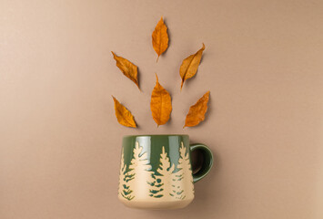 Mug with autumn leaves on beige background. Flat lay, top view.