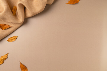 Brown fabric with leaves on beige as concept background. Copy space