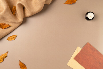 Brown fabric with leaves, envelope, candle on beige as concept background. Copy space
