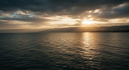Fototapeta premium Sea of Galilee at sunset with golden light illuminating the water