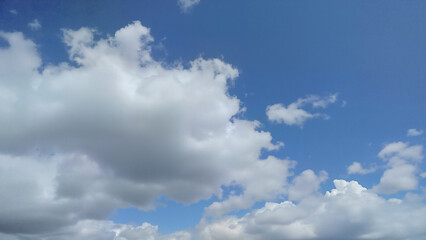 Obraz premium White clouds isolated against a clear blue sky, perfect for backgrounds or weather concepts. Ideal for illustrating calm, peaceful, and natural outdoor scenes.