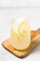Limoncello spritz - refreshing cocktail served in a clear glass garnished with a lemon slices. The drink is placed on a wooden board next to fresh lemons, creating a summery feel and holiday vibes.