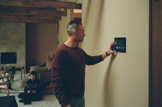 Man adjusting temperature of house through smart home app at home