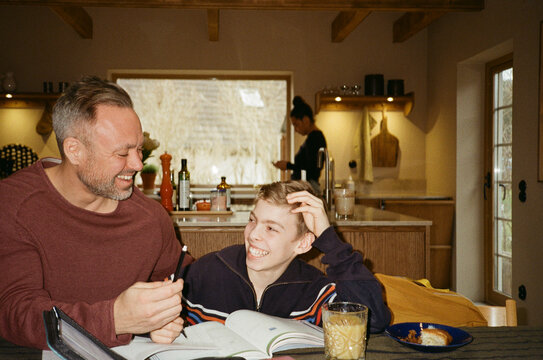 Son laughing with father while studying at home