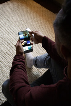 High angle view of man scrolling application on smart phone at home