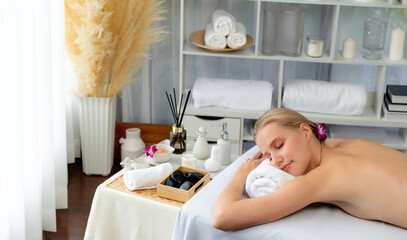 Caucasian woman customer enjoying relaxing anti-stress spa massage and pampering with beauty skin recreation leisure in day light ambient salon spa at luxury resort or hotel. Quiescent