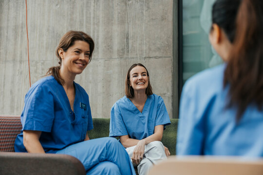 Smiling female healthcare workers spending leisure time talking with each other in hospital building