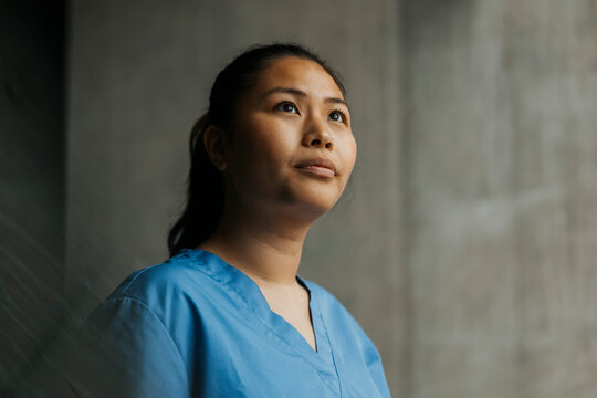Thoughtful young female healthcare worker looking away