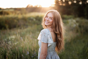 Beautiful and smiling girl in a field on a summer evening.