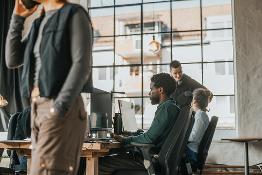 Focused male computer programmer coding on desktop PC while sitting at desk in tech hub