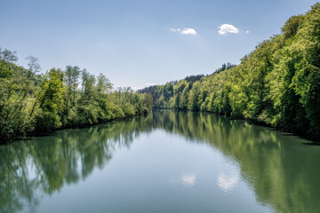 Obraz premium Ruhiger Flusslauf der Kupa, gesäumt von grünen Ufern unter blauem Himmel