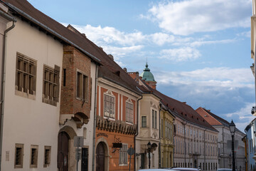 Obraz premium Old houses along the street in Buda Castle District, Budapest, Hungary. Dome of Mary Magdalene Tower or Buda Tower