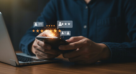 Person holding a smartphone with review bubbles and stars above it next to a laptop on a wooden desk