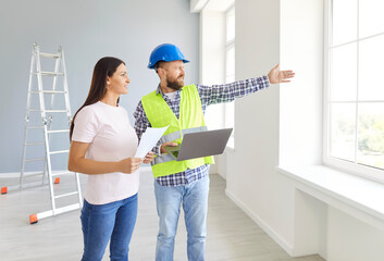 Professional architectural engineer and woman apartment owner looking out window and talking about...