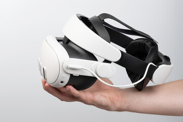 Fototapeta premium Hand holding VR headset against plain background, highlighting modern tech