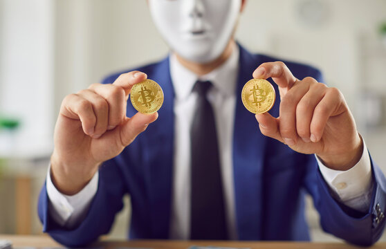 Golden bitcoin coins in the hands of a man in a mask close up. Crypto currency gold coin with a bitcoin symbol in the hands of a man in a business suit. Bitcoin invest crypto currency concept