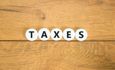 Taxes symbol. Concept word Taxes on beautiful white pills circles. Beautiful wooden table wooden background. Business lifestyle taxes concept. Copy space.