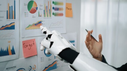 A robotic arm interacts with various infographics and charts in a contemporary office setting, highlighting the integration of technology in data analysis and decision-making.Noogenesis