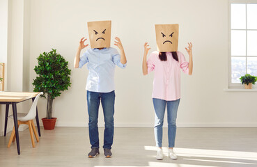 Couple with brown paper bags on their heads with angry and upset facial expressions painted on...