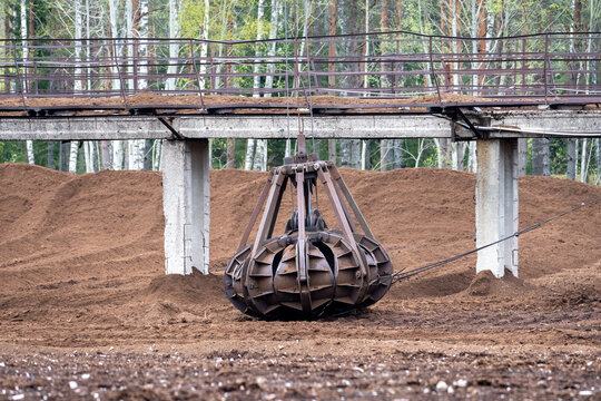 Rusty Mechanical Grapple in Peat Storage Yard – Close-Up of Excavator Attachment Used in Material Handling