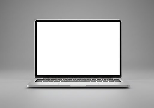 A laptop with a blank white screen sits on a gray surface in front of a gray background studio shot