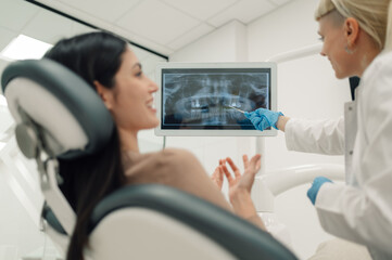 Dentist showing teeth x ray to patient in modern clinic