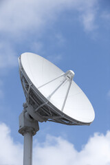 Satellite dish stands tilted upwards against a blue sky, capturing signals. Communication technology, signal reception, sky observation