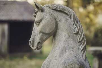 Close-up of a weathered stone horse sculpture outdoors.