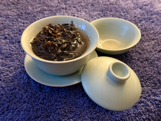 Cup or tea glass hot brew and dried tea leaves. Brewing Chinese tea in ceramic gaiwan during the tea ceremony. 