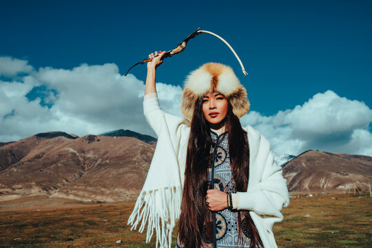 Young traditional kyrgyz woman with whip in hand portrait in high mountains