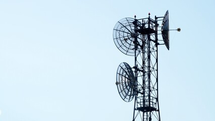 Telecommunication tower with multiple antennas and parabolic dishes and panel antennas, stands against a vast, cloudless sky, symbolizing connectivity and broadcasting © DVisions