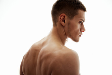 Naklejka premium A portrait of a young fit man showcasing his back and neck muscles against a bright white background, highlighting physical strength, confidence, and a healthy lifestyle.
